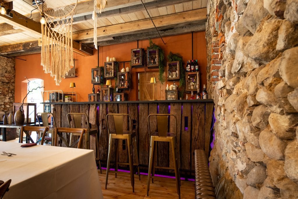 Gemütliche Bar in rustikalem Ambiente mit Steinmauer und warmen Holzdekoren, ideal für gesellige Abende.