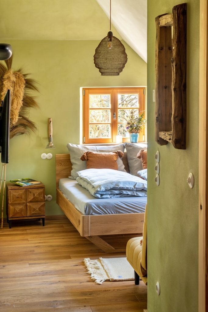 Gemütliches Schlafzimmer mit Naturholzmöbeln und grünen Wänden, ideal für entspanntes Wohnen bei Gut Leben Berlin.
