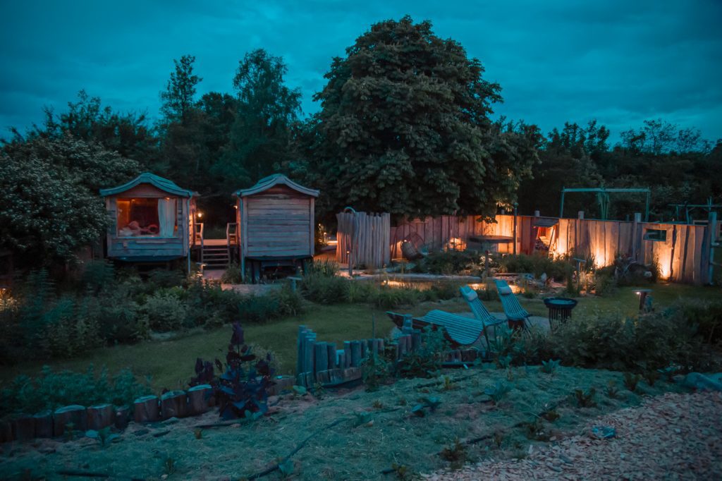 Entspannter Garten mit kleinen Holz-H&auml;uschen, gem&uuml;tlicher Beleuchtung und Naturverbundenheit.