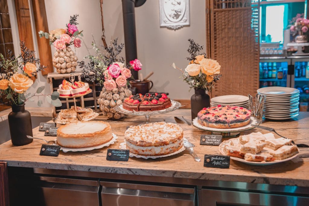 Genussvolle Kuchentafel mit frischen Desserts und Blumenarrangements bei Gut Leben in Berlin.