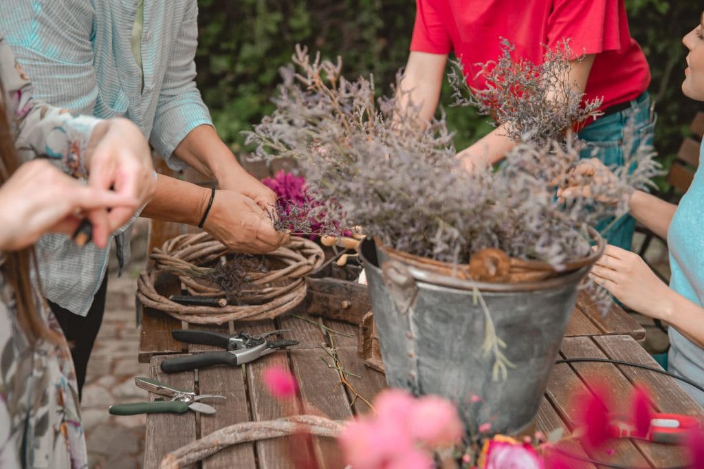Frühjahrskunst im Garten: Menschen erstellen Trockenblumensträuße für nachhaltige Dekoration.