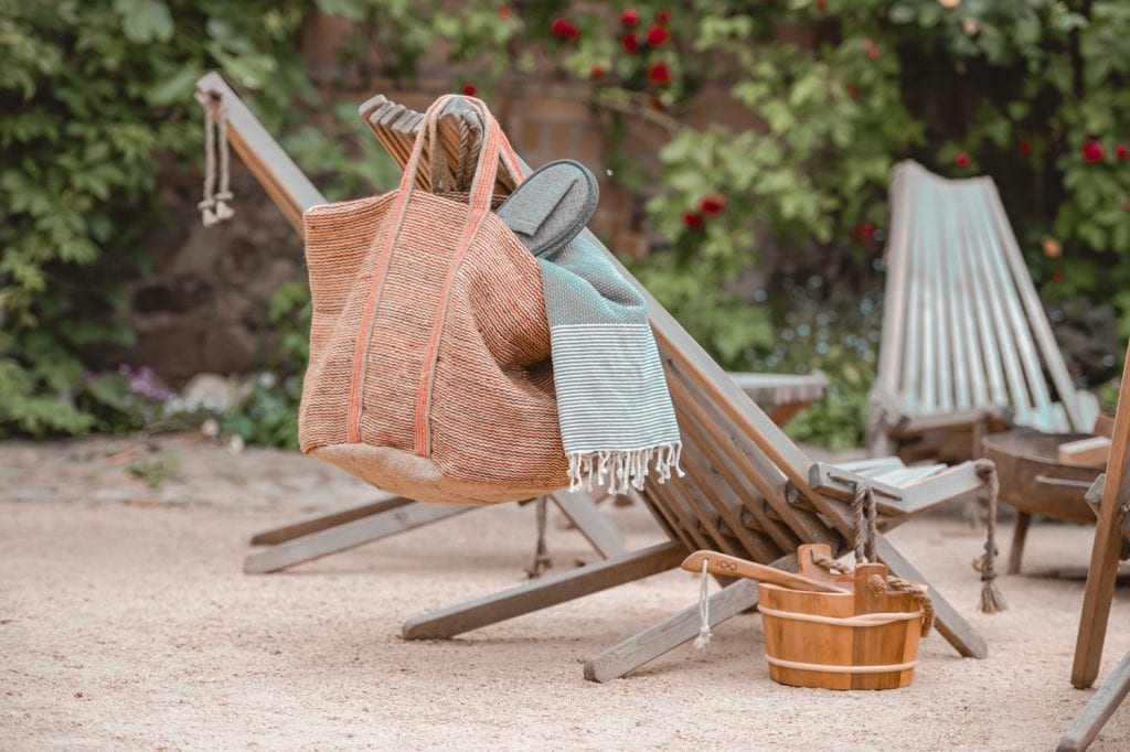 Entspannter Strandstuhl mit Tasche und Handtuch im gartenähnlichen outdoor Bereich.