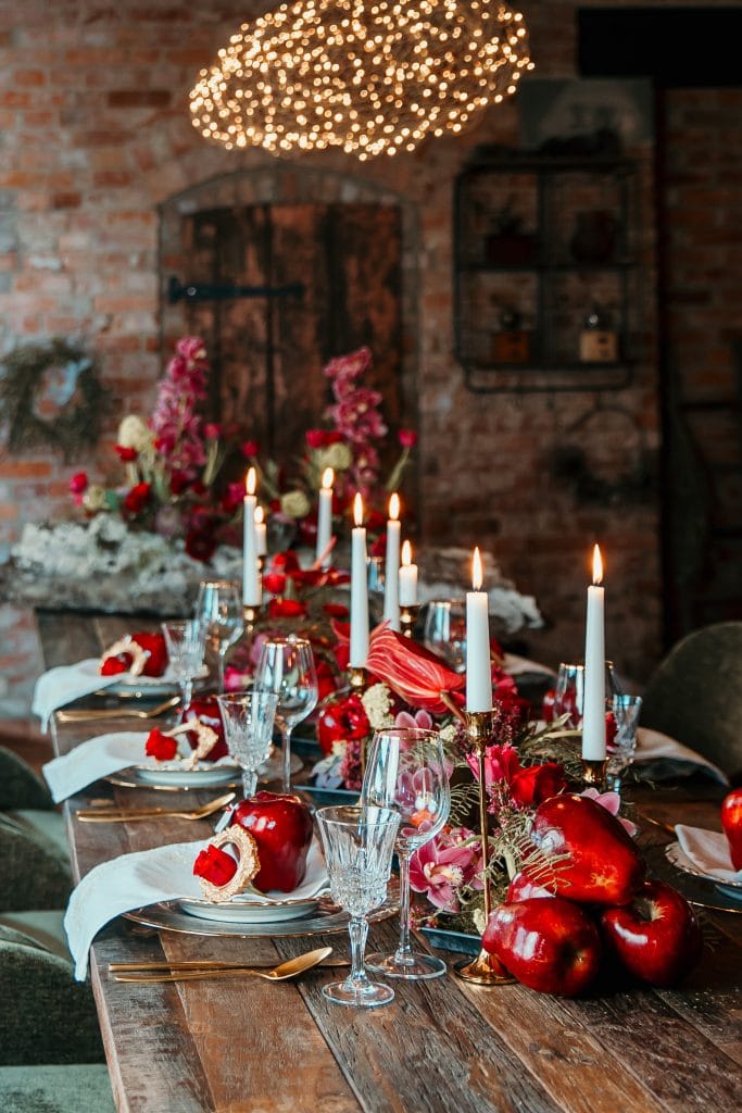 1. Eleganter festlicher Tisch mit Kerzen, Blumen und Äpfeln in rustikaler Atmosphäre.