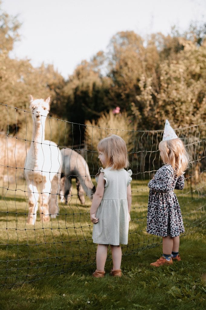 Fröhliche Kinder beim Tierkontakt auf dem Bauernhof, Naturerlebnis für Kinder rund um gesunde Lebensweise.