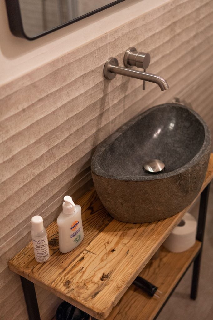 Nat&uuml;rliche Steinwaschschale mit moderner Wasserhahn am Wand, nachhaltige Badezimmergestaltung.