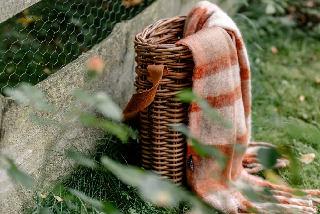 Gemütliche Woll-Decke auf Korb im Garten, ideal für Natur- und Entspannungspausen.