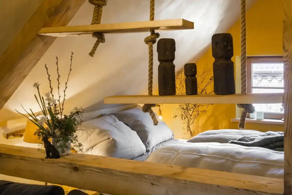 Gem&uuml;tliches Schlafzimmer mit Holzdecke und Dekorationen nach Prinzipien des guten Lebens.