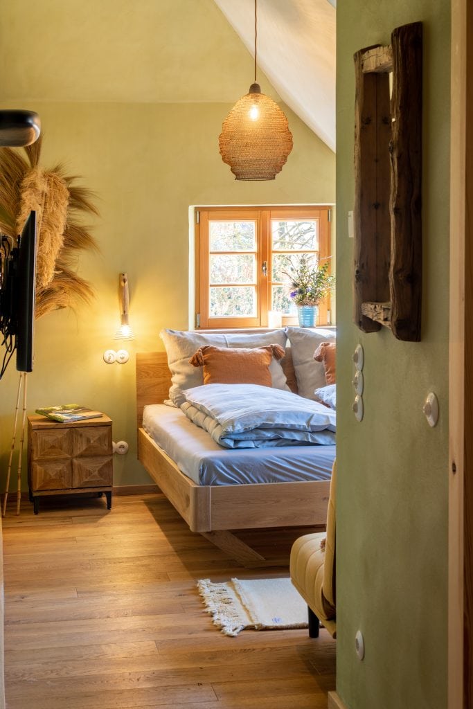 Gem&uuml;tliches Schlafzimmer mit nat&uuml;rlichem Holzdesign und viel Tageslicht, ideal f&uuml;r erholsamen Schlaf.