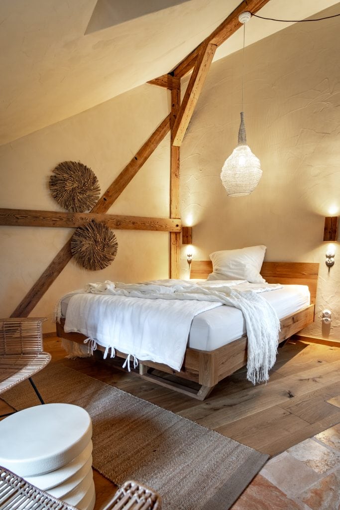 Gemütliches Schlafzimmer mit natürlichem Holzdekor und Dachschräge, ideale Rückzugsort im Gut Leben Berlin.