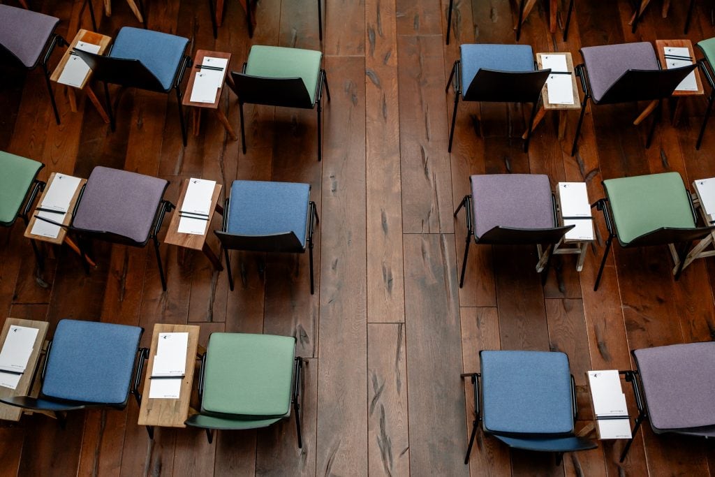 Verschiedene Stühle mit bunten Sitzkissen und Tafelaufschriften in einem eleganten Veranstaltungssaal.