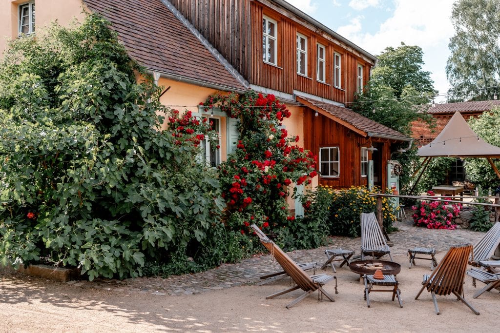 Gemütliches Haus mit Garten, hochwertige Holzmöbel und blühende Pflanzen, perfekter Ort für nachhaltiges Leben.