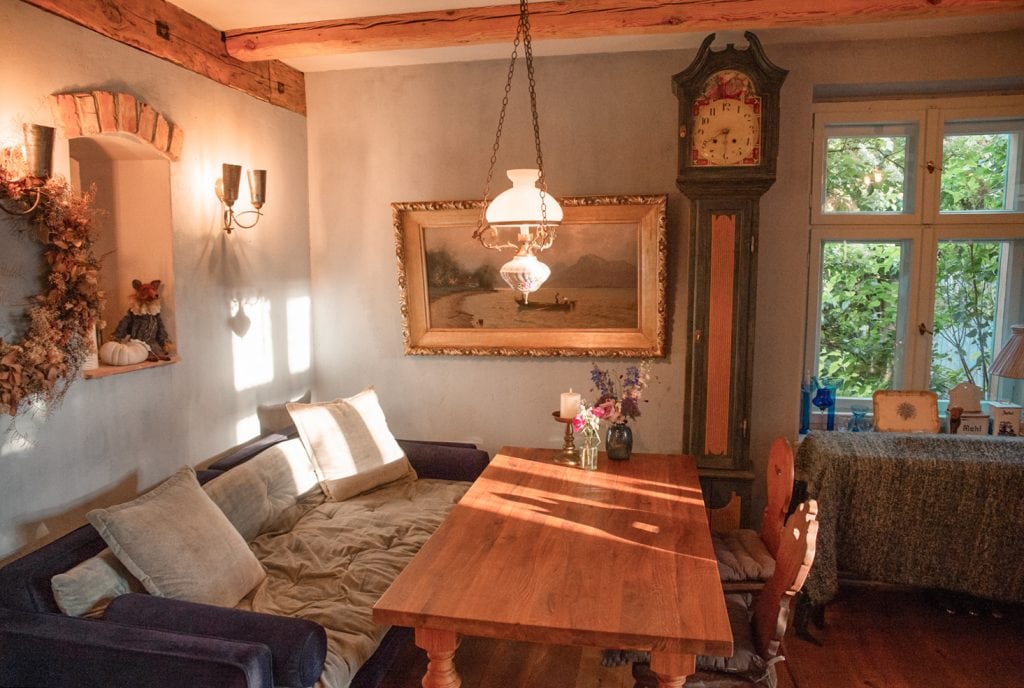 Gemütlicher Wohnraum mit rustikalem Charme, alte Uhr und liebevolle Dekorationen, ideal für nachhaltiges Leben.