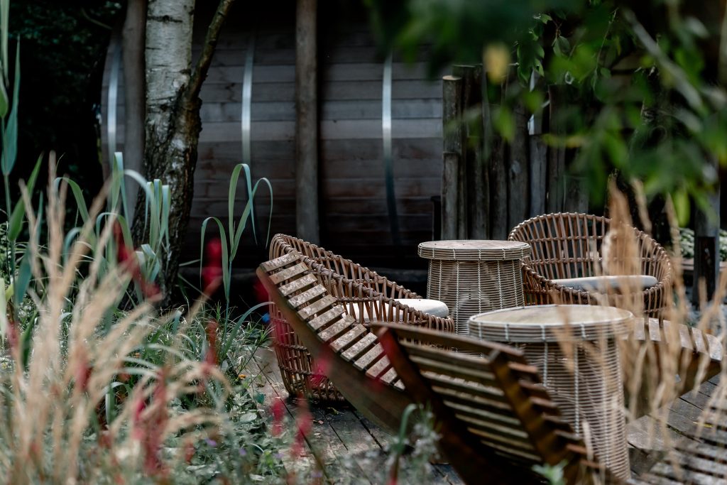 Entspannter Gartenbereich mit stilvollen Rattanm&ouml;beln und nat&uuml;rlichem Ambiente.