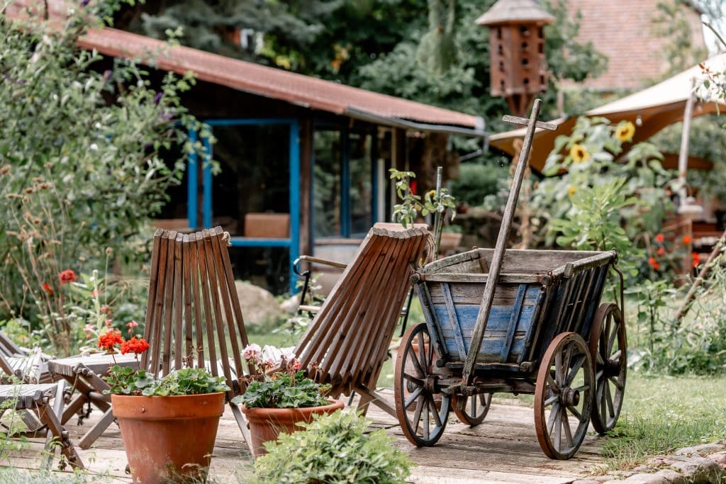 Gemütlicher Außenbereich mit Antik-Wanderwagen, Terrakottatöpfen und Naturgartenideen für nachhaltiges Leben.