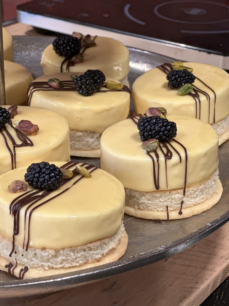 Saftige Mandeltörtchen mit weißen Schokolade-Glasur, schwarzen Brombeeren und Pistazien.