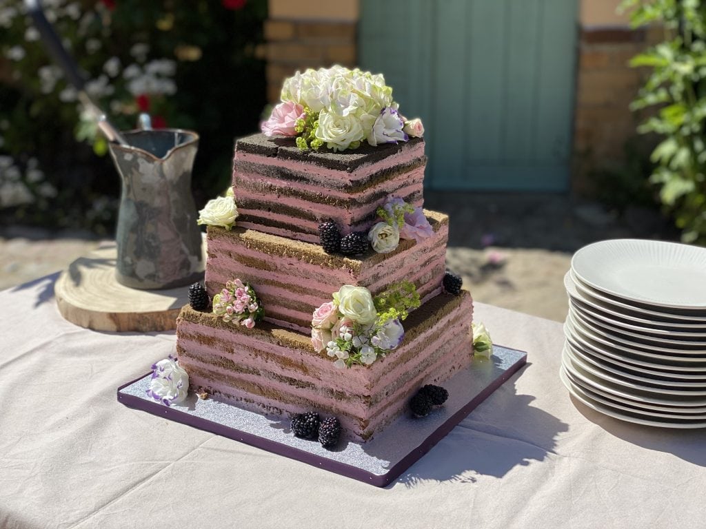 Frischer, mehrst&ouml;ckiger Hochzeitstorte mit Blumen und Beeren, perfekt f&uuml;r festliche Anl&auml;sse.