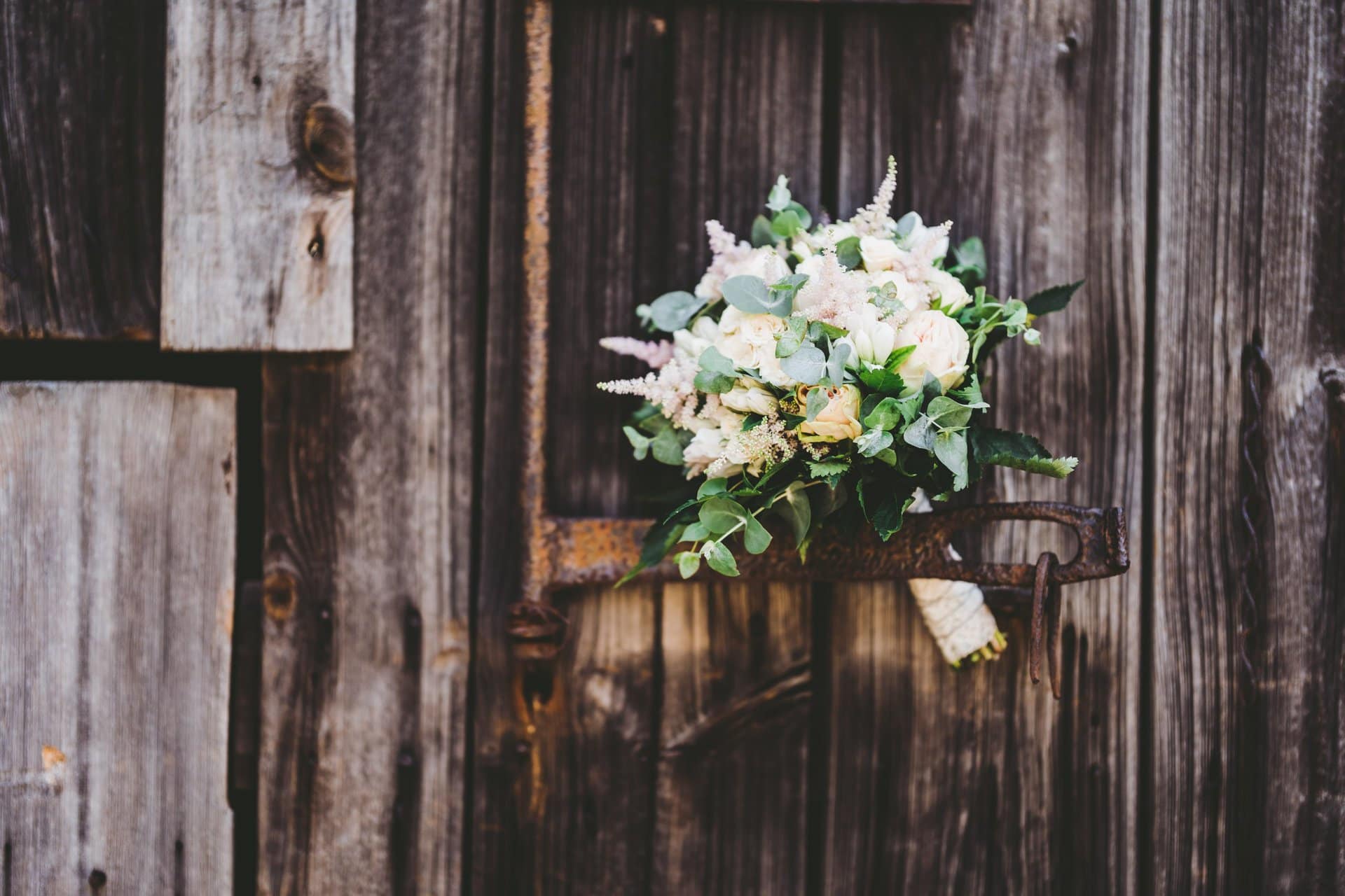 Natürliche Hochzeitsblumen auf rustikaler Holzvorgartenwand.