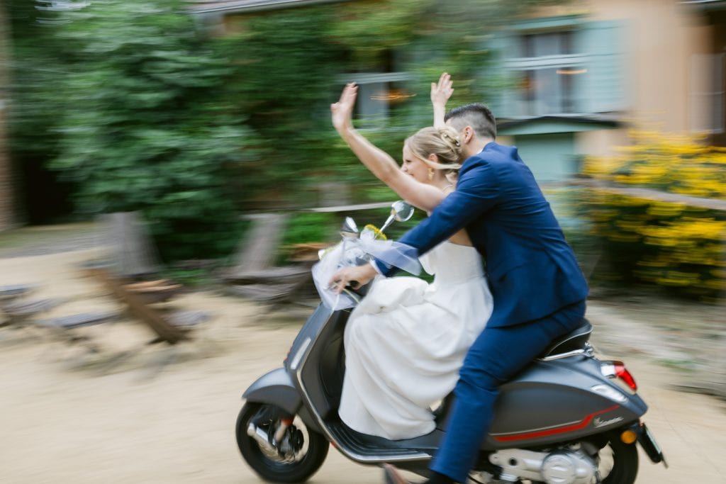 Frisch verheiratetes Paar auf Vespa bei Hochzeitsfahrt in Berlin.