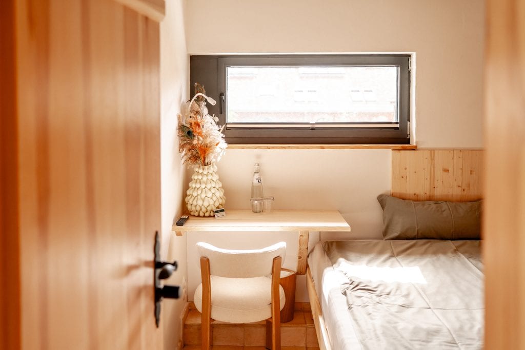 Gem&uuml;tliches Schlafzimmer mit Naturholzm&ouml;beln und Fensterblick, ruhige Atmosph&auml;re, nachhaltiges Wohnen.