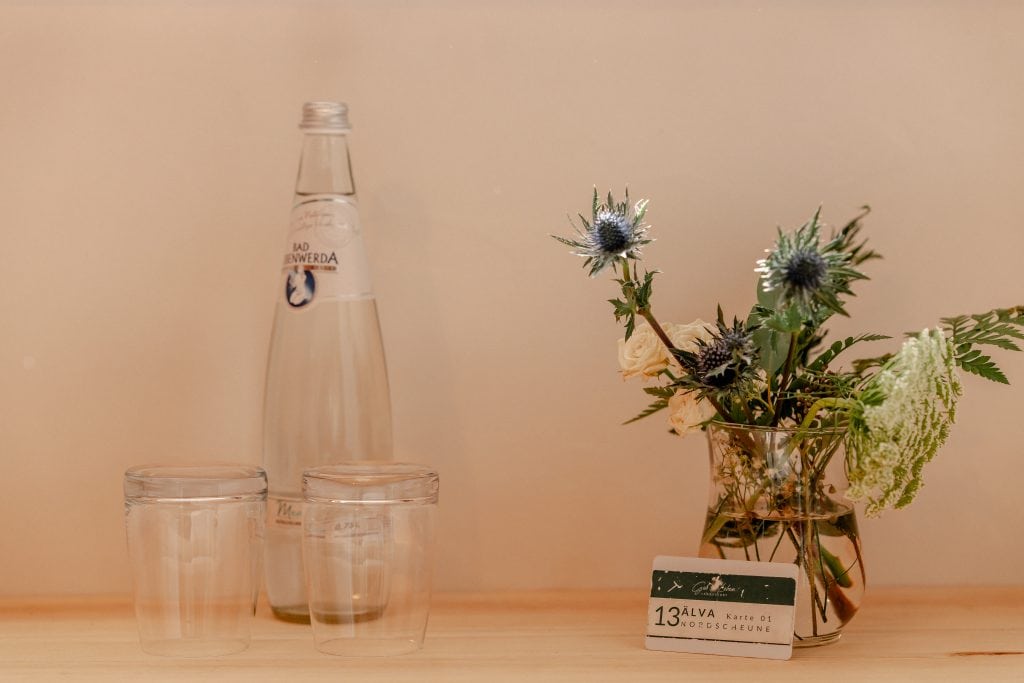 Frische Mineralwasserflasche mit Gl&auml;sern und Blumenstr&auml;u&szlig;e f&uuml;r gesundes Leben in Berlin.