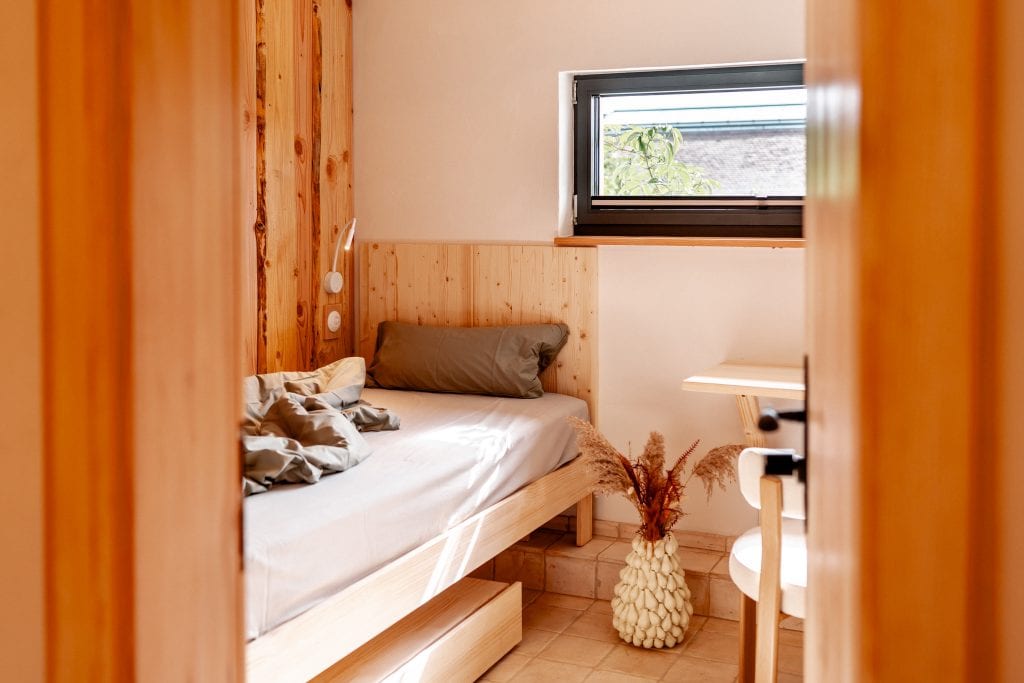 Gem&uuml;tliches Schlafzimmer mit Naturholz, viel Licht und nat&uuml;rlicher Dekoration, ideal f&uuml;r erholsamen Schlaf.