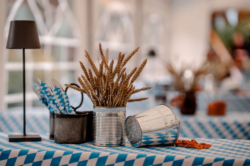 Gem&uuml;tliche Tischdekoration mit Weizen, Blau-Wei&szlig;-Design und traditionellem Oktoberfest-Ambiente.