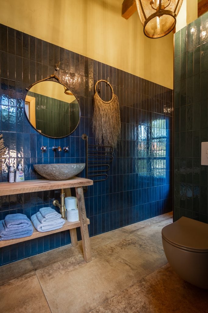 Natürliche Badezimmergestaltung mit dunkelblauen Fliesen und Holz-Accessoires.