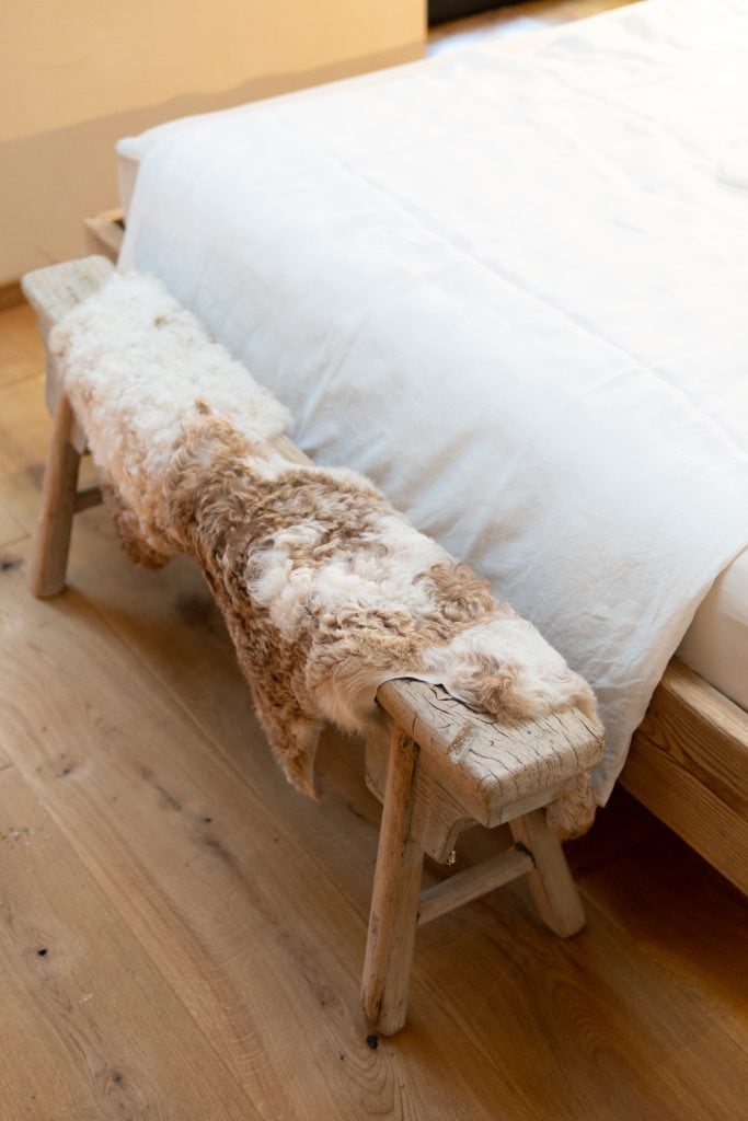 Gemütliche Liegedecke aus Naturfasern auf Holzbank im Schlafzimmer.