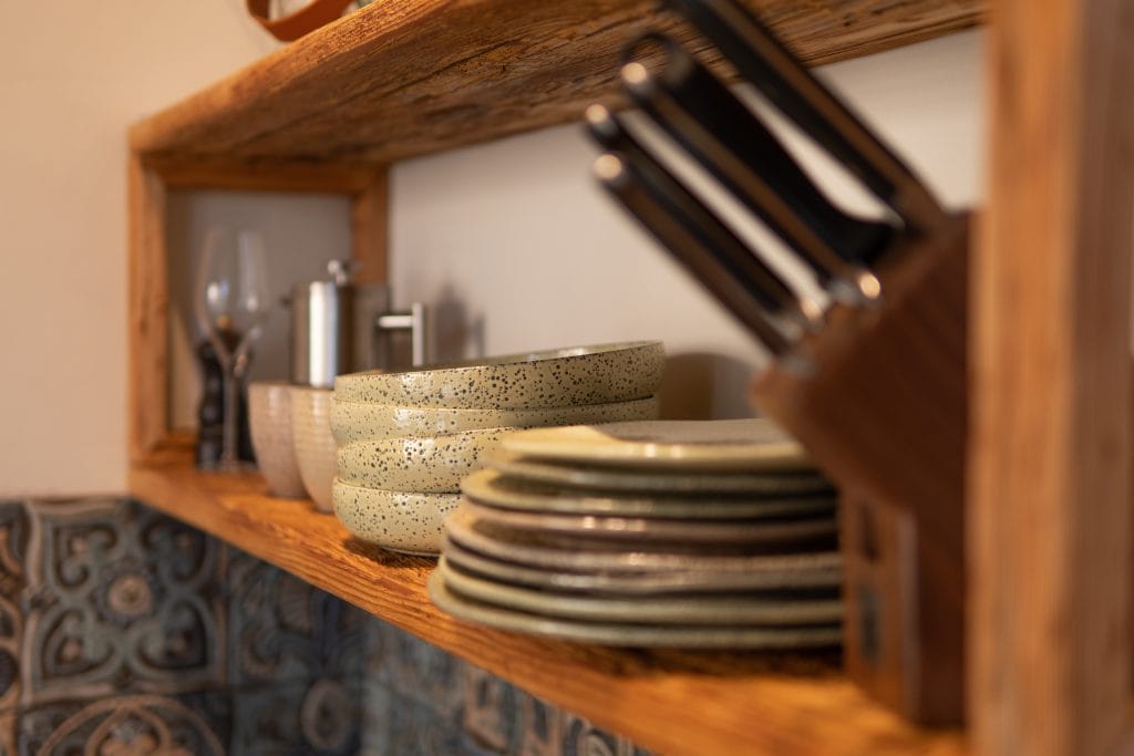 Bequeme Esstafel, handgefertigte Geschirr mit nachhaltigem K&uuml;chenstil, offene Regale, nat&uuml;rliche Holzdekoration.