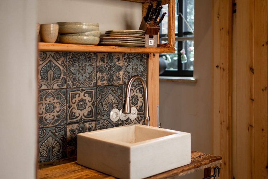 Nat&uuml;rliche K&uuml;chenewand mit handgefertigtem Waschbecken und rustikalem Holzdesign.