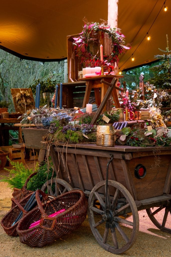 Elegant kreativ gestaltete Weihnachtsdekoration auf einem alten Holzwagen mit Kerzen, Tannenzweigen und Christbaumschmuck.