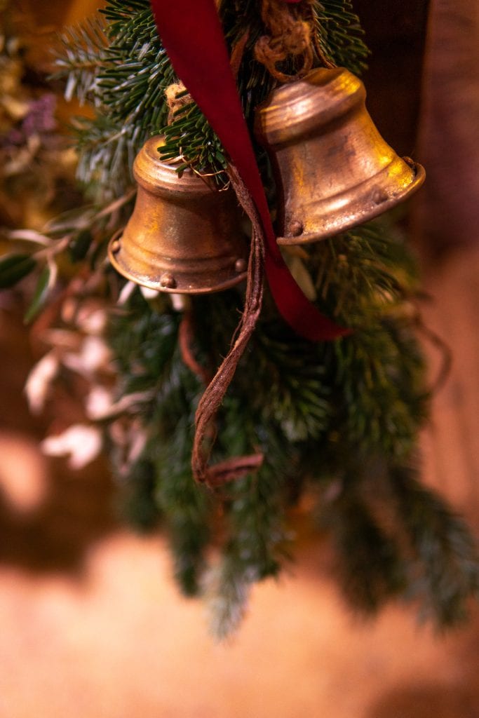 Goldene Weihnachtsglocken an Tannenzweig, festliche Dekoration f&uuml;r besinnliche Feiertage.