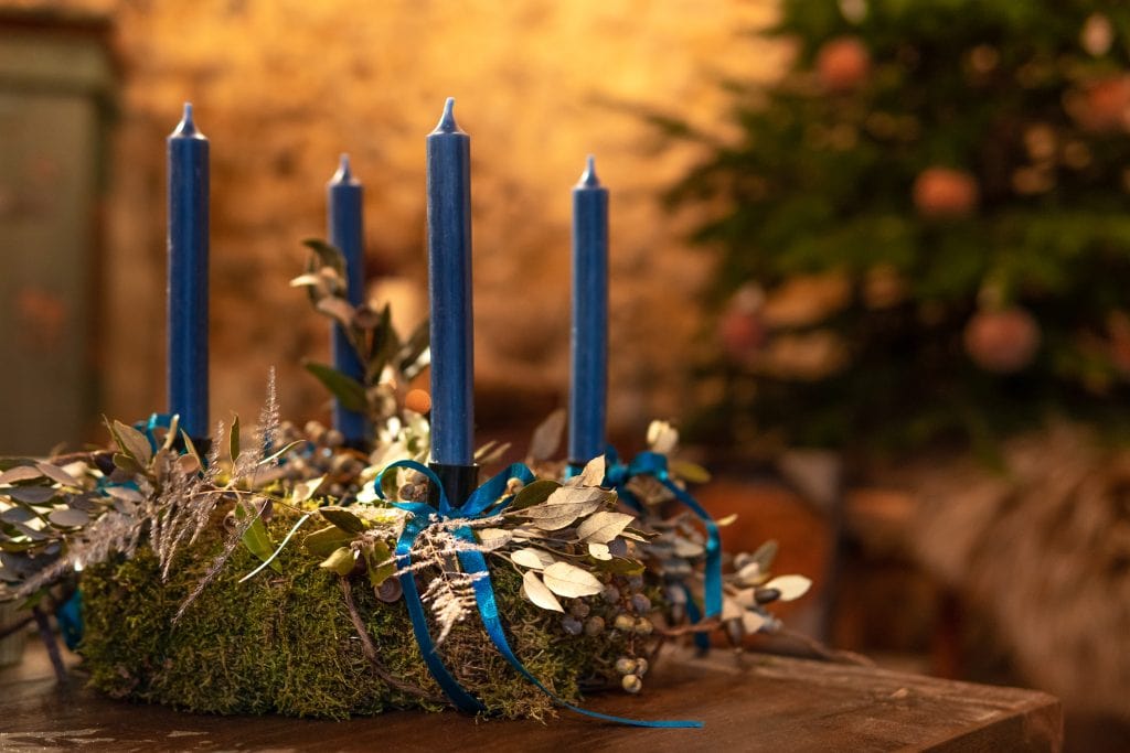Blaue Adventskerzen mit Naturdekoration, festliche Stimmung, nachhaltiges Weihnachtsdesign.