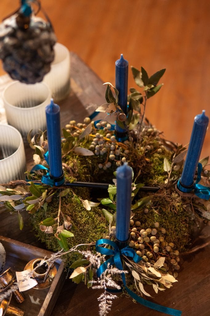 1. Dekorative Adventskranz mit blauen Kerzen, Naturmaterialien und Tannenzapfen.
