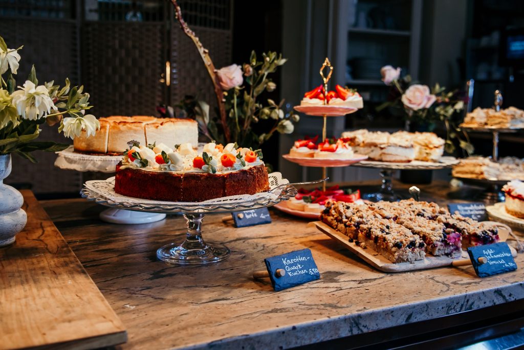 Vier k&ouml;stliche Kuchen und Desserts auf einer festlich gedeckten Tafel bei Gut Leben Berlin.