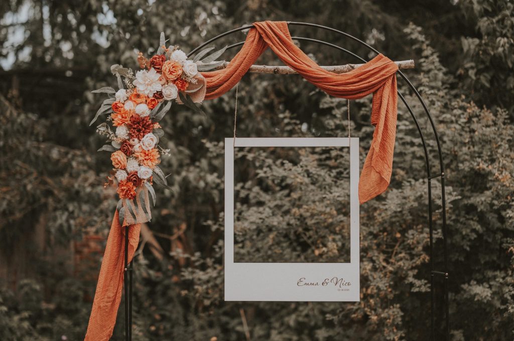 Blumen-Dekoration für Hochzeit im Garten mit personalisiertem Rahmen, festliche Atmosphäre, stilvoll und elegant.