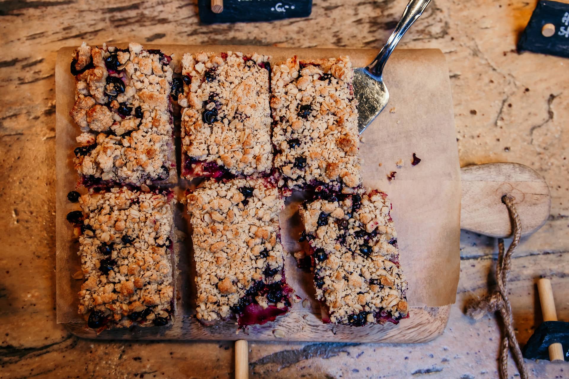Frischer Beeren-Vanille-Crumble-Kuchen auf rustikalem Holzbrett, Bio-Dessert, Gut Leben Berlin.