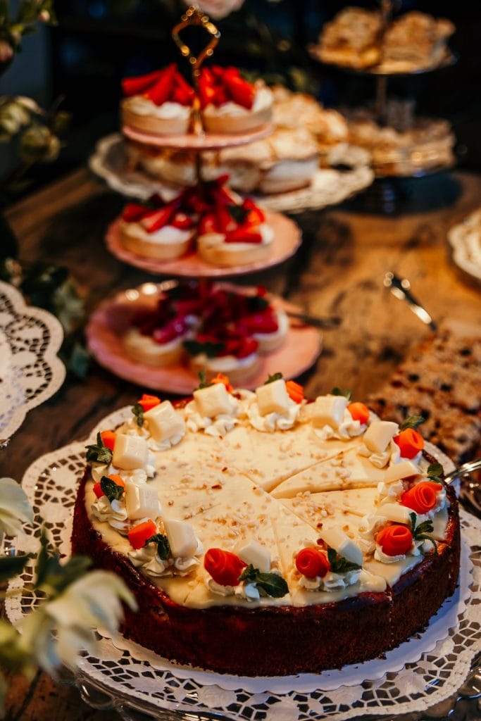 Verf&uuml;hrerischer K&auml;sekuchen mit wei&szlig;en Schokoladenrosen und frischen Beeren, perfekt f&uuml;r festliche Anl&auml;sse.