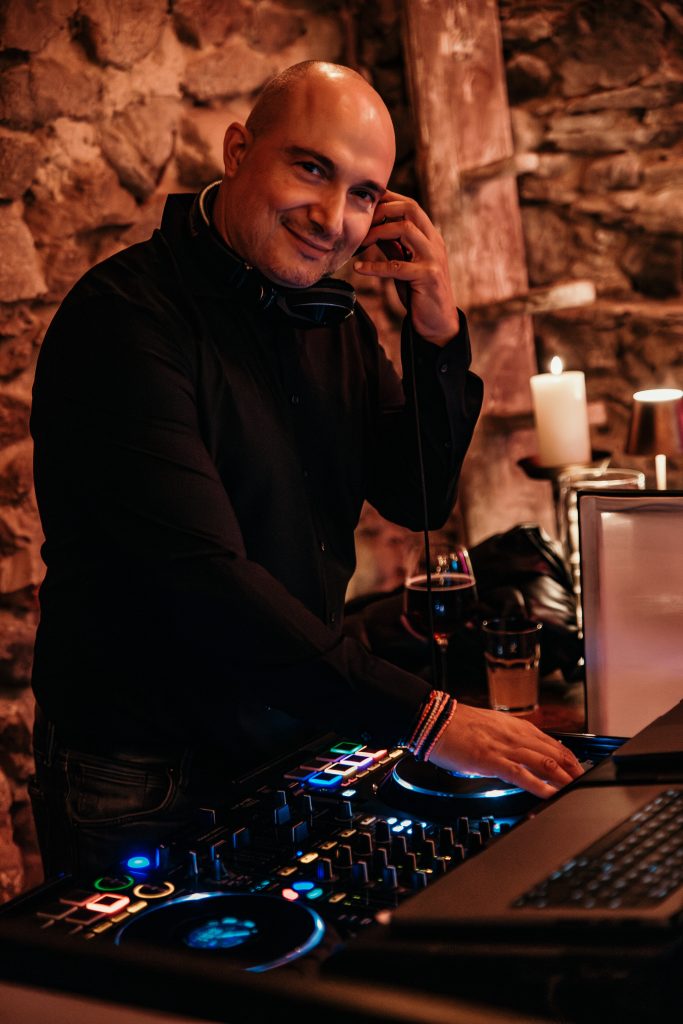 1. DJ beim Auflegen in einem gemütlichen Raum mit Steinwänden und Kerzen.