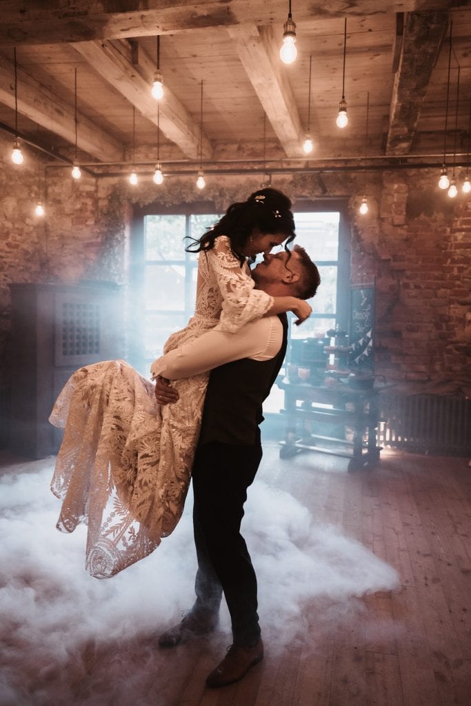 1. Hochzeitspaar bei Tanz in rustikaler Location mit warmem Licht.