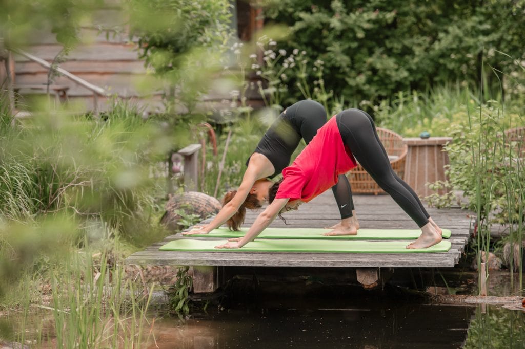 Entspanntes Yoga im Grünen auf einer Holzbrücke im Garten.