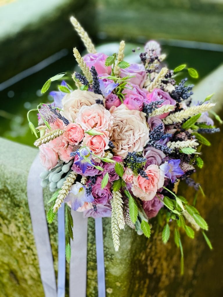 Farbenfrohes Blumengesteck mit Rosen, Lavendel und Gr&auml;sern f&uuml;r nat&uuml;rliches Wohlbefinden.