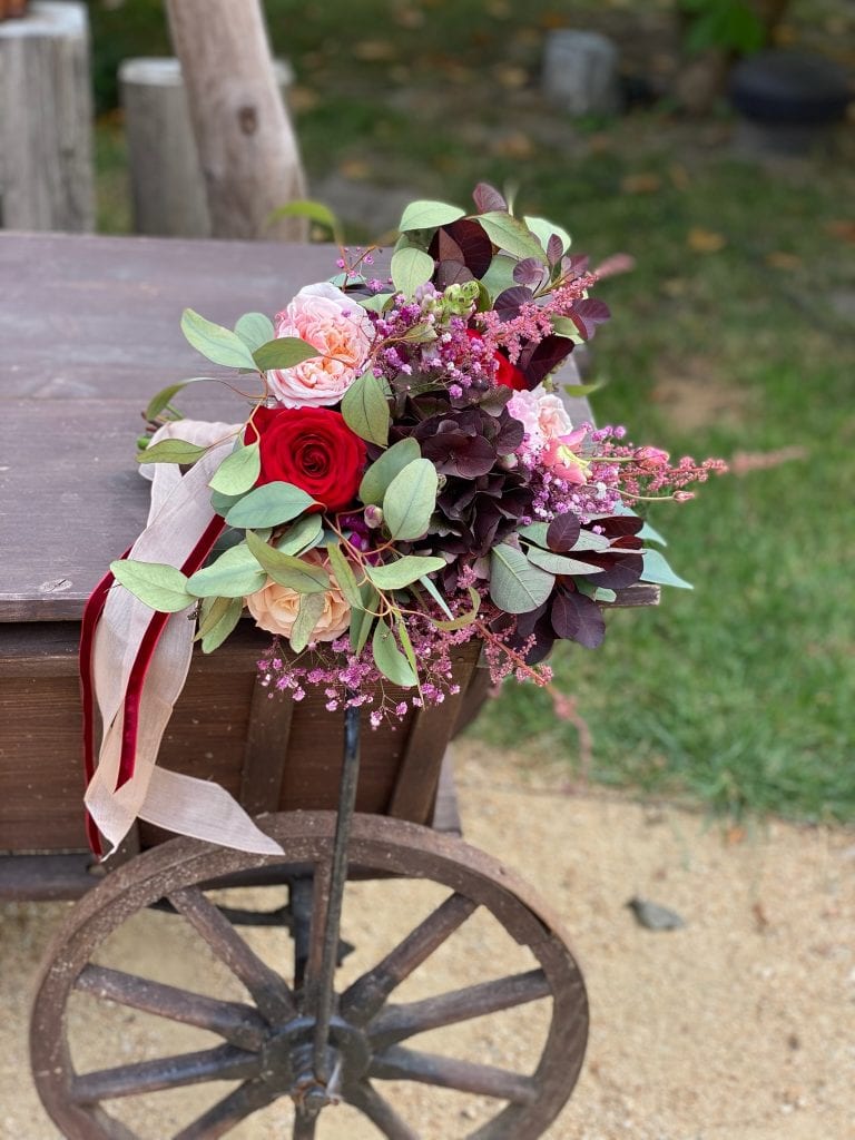 Fr&uuml;hling: Rosen, Eukalyptus und Blumenarrangement auf Holzwagen.