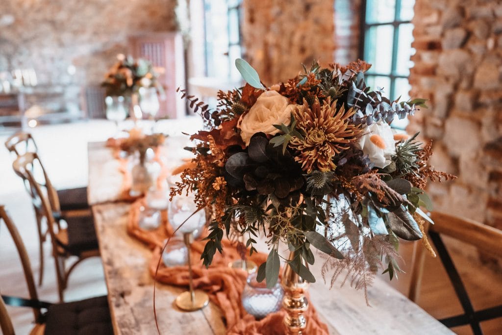 Elegante Herbstblumen Dekoration auf Tafel, rustikales Ambiente, Hochzeits- oder Event-Tischdeko.