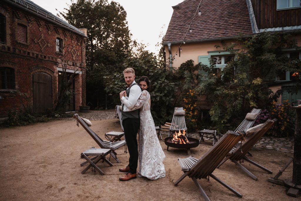 Entspannendes Hochzeitsfoto im Garten mit Lagerfeuer bei Sonnenuntergang.