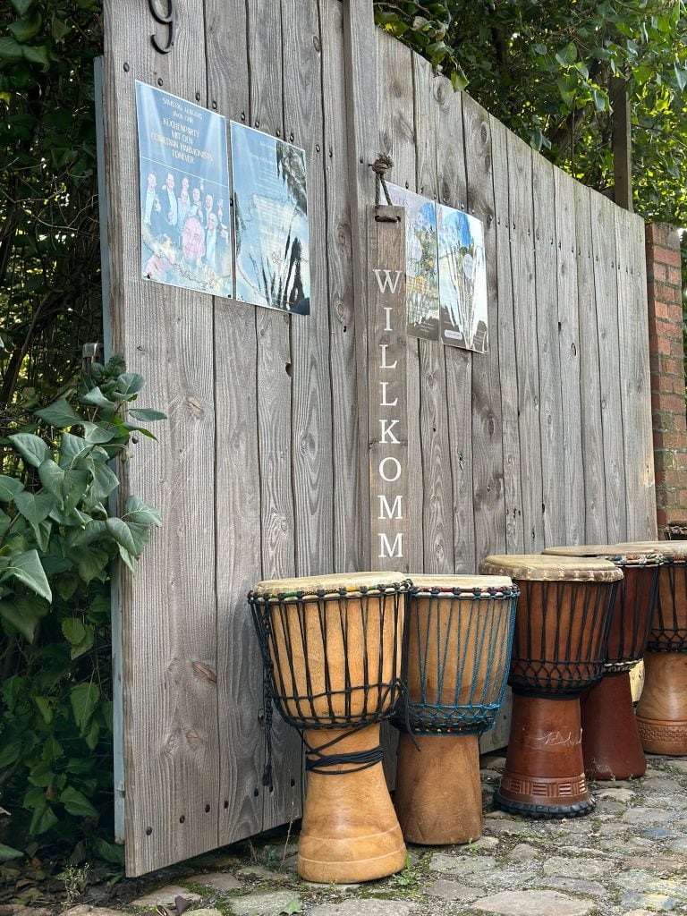 Fr&ouml;hliche Musik-Drum-Performance vor einer Holzwand bei Gut Leben Berlin.