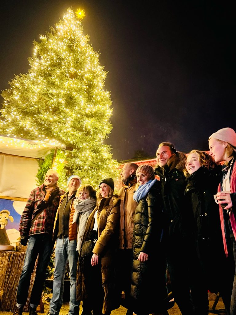 Festlicher Weihnachtsbaum mit Beleuchtung bei Gut Leben Berlin, fr&ouml;hliche Menschen genie&szlig;en Weihnachtsstimmung.