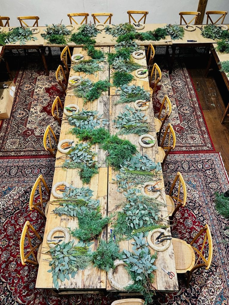 Hochzeitstisch mit nat&uuml;rlichen Gr&uuml;ndekorationen, rustikaler Holzoptik, einladende Atmosph&auml;re.