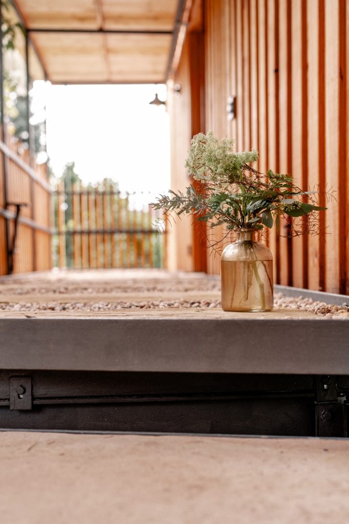 Stilvolle Holzterrasse mit Blumenvasen f&uuml;r nachhaltiges Leben und Entspannung.