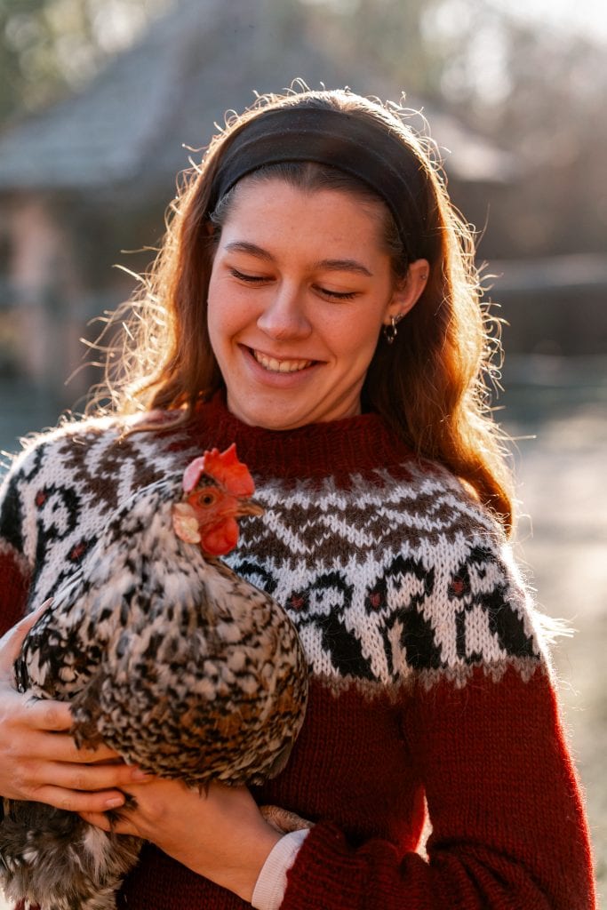 Fr&ouml;hliche Frau h&auml;lt gl&uuml;ckliches Huhn, Natur und Tierwohl, nachhaltiges Leben, tierfreundliche Lebensweise.